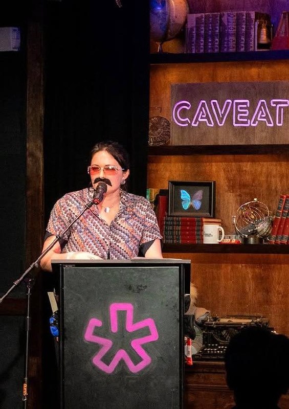 Willa Barnett hosting a science comedy night at Caveat, in costume at the podium
